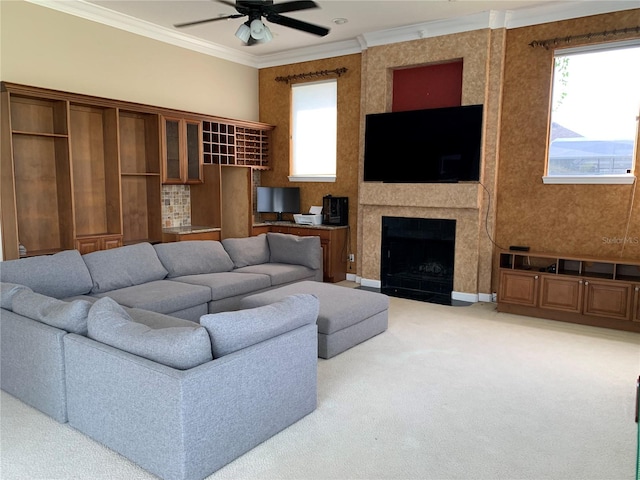 carpeted living room featuring ceiling fan, a large fireplace, and ornamental molding