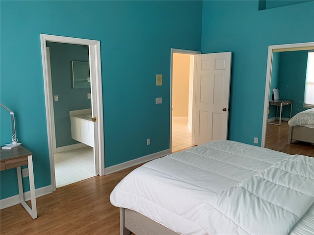 bedroom featuring connected bathroom, a high ceiling, and tile patterned flooring