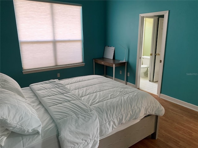 bedroom with ensuite bath and wood-type flooring