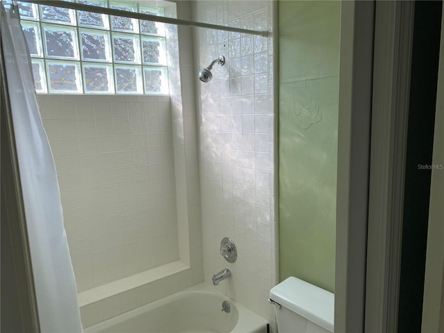 bathroom featuring toilet, plenty of natural light, and shower / bath combo with shower curtain