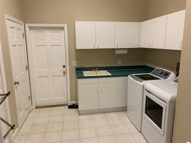 washroom with light tile patterned floors, sink, washing machine and dryer, and cabinets