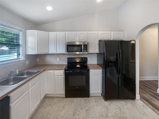 kitchen with vaulted ceiling, sink, black appliances, white cabinets, and tasteful backsplash