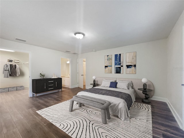 bedroom with a spacious closet, dark wood-type flooring, a closet, and ensuite bathroom