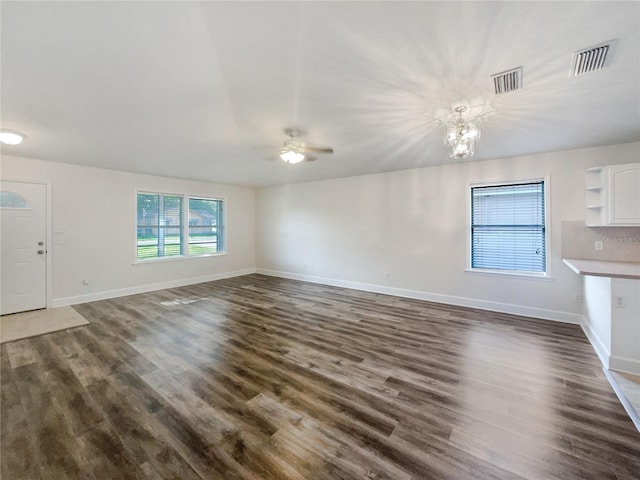 unfurnished living room featuring ceiling fan with notable chandelier and dark wood-type flooring