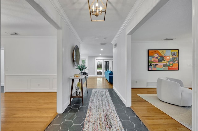 foyer entrance featuring visible vents, crown molding, and wood finished floors