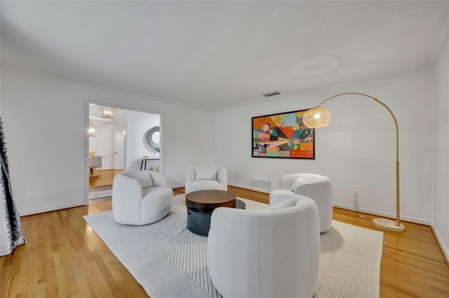 living room with baseboards, arched walkways, visible vents, and light wood-style floors