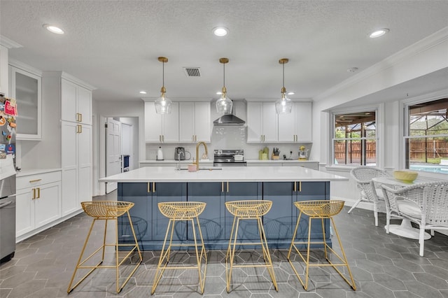 kitchen featuring wall chimney exhaust hood, appliances with stainless steel finishes, visible vents, and light countertops