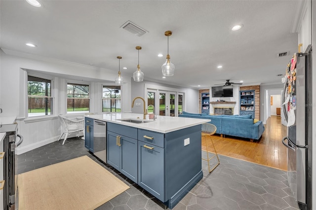 kitchen featuring a fireplace, blue cabinetry, visible vents, appliances with stainless steel finishes, and a sink