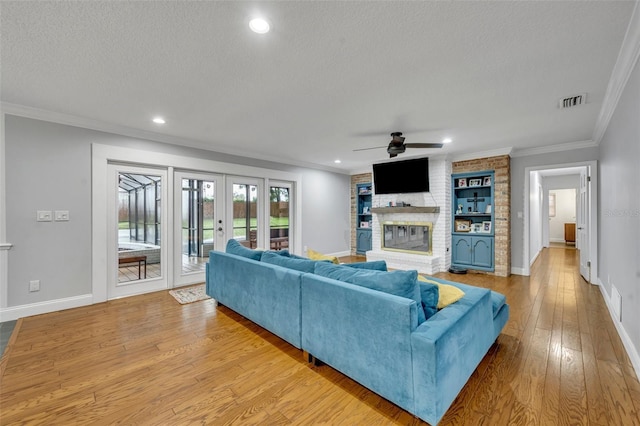 living area with hardwood / wood-style flooring, ornamental molding, a textured ceiling, french doors, and a fireplace