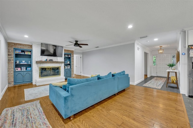 living room featuring a fireplace, wood finished floors, visible vents, baseboards, and crown molding