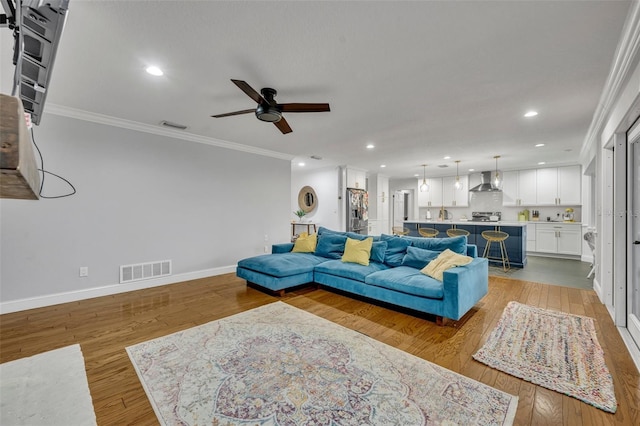 living room with ornamental molding, wood-type flooring, and visible vents