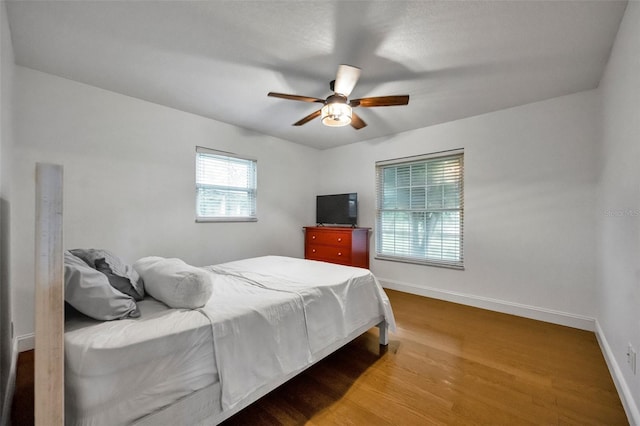 bedroom with a ceiling fan, baseboards, and wood finished floors