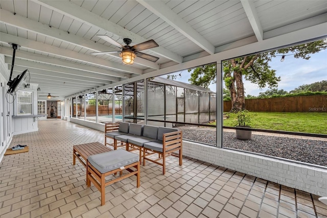 unfurnished sunroom with beamed ceiling, plenty of natural light, and a ceiling fan