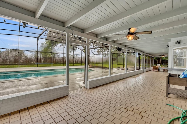 unfurnished sunroom with a healthy amount of sunlight, ceiling fan, and beamed ceiling