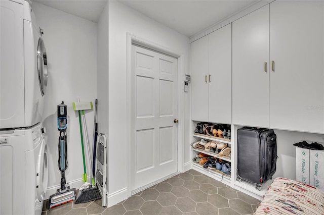 mudroom featuring baseboards, dark tile patterned flooring, and stacked washer / drying machine