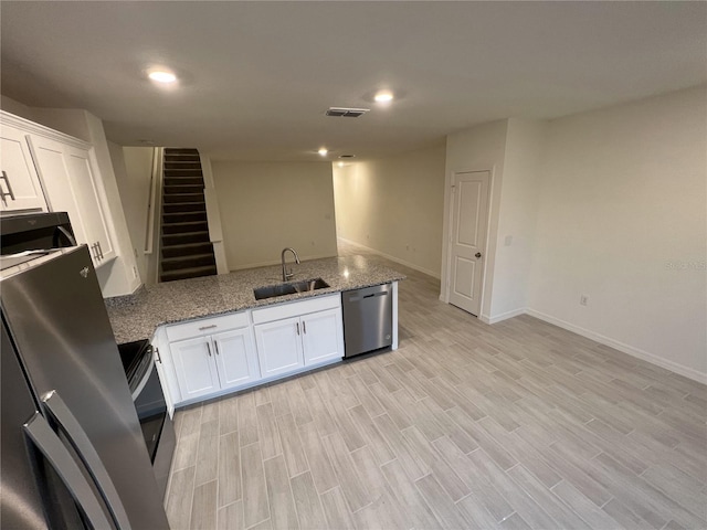 kitchen with light stone countertops, white cabinetry, sink, and appliances with stainless steel finishes