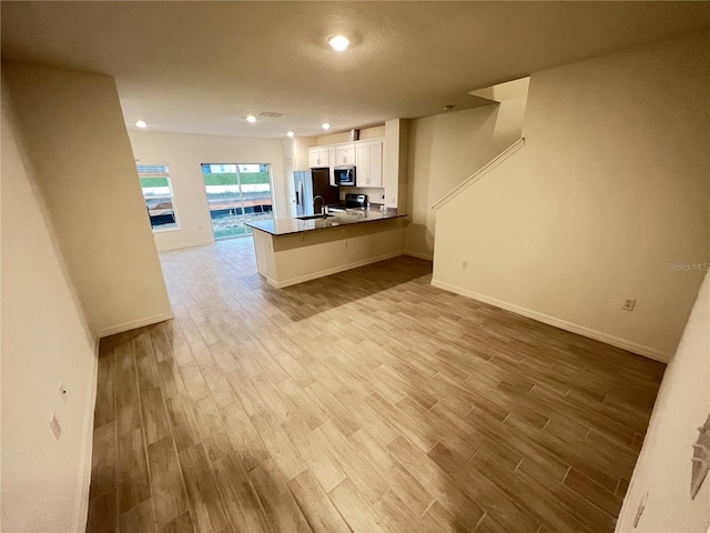 kitchen featuring white cabinets, kitchen peninsula, stainless steel appliances, and light hardwood / wood-style flooring