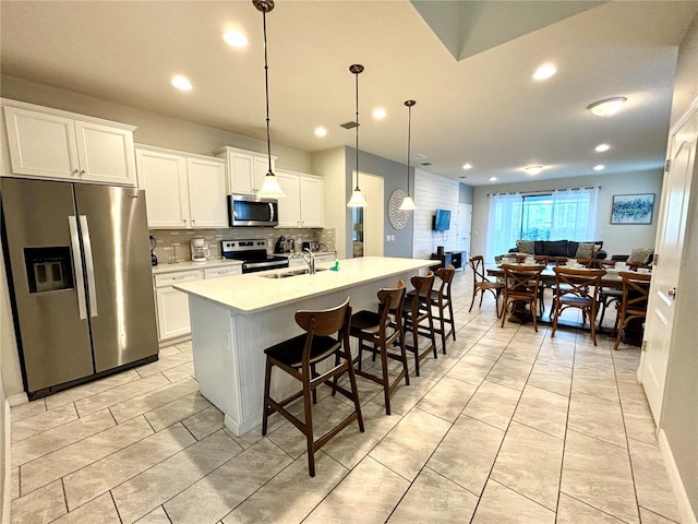 kitchen featuring a kitchen island with sink, stainless steel appliances, and white cabinetry