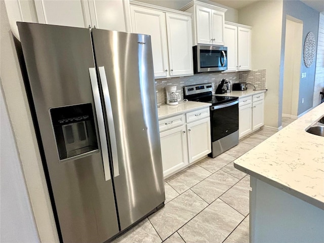 kitchen featuring appliances with stainless steel finishes, light stone counters, decorative backsplash, and white cabinets