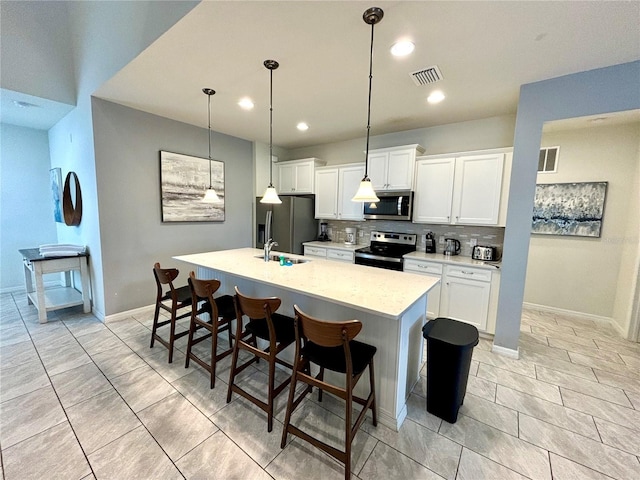 kitchen with a kitchen breakfast bar, backsplash, appliances with stainless steel finishes, a kitchen island with sink, and light tile patterned floors