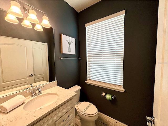 bathroom with toilet, an inviting chandelier, and vanity