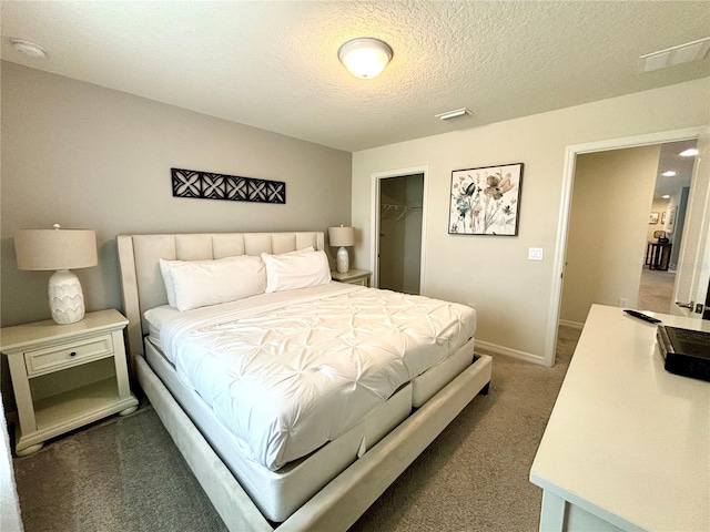 bedroom featuring a walk in closet, a closet, a textured ceiling, and carpet flooring