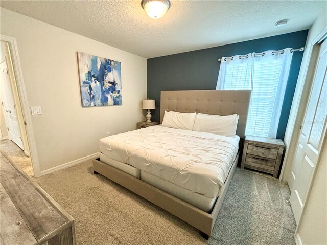 bedroom with a textured ceiling, carpet flooring, and a closet