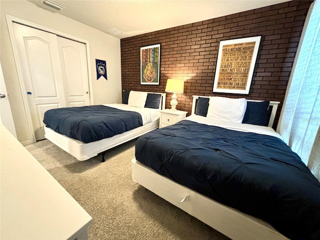 bedroom with a closet, brick wall, and light colored carpet