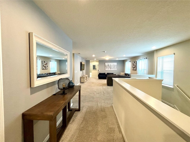 hallway featuring a textured ceiling and light carpet