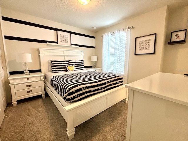 bedroom with a textured ceiling and dark colored carpet