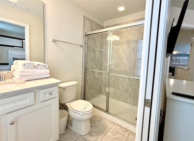 bathroom with tile patterned flooring, vanity, walk in shower, and toilet