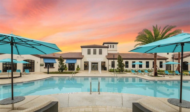 pool at dusk featuring a patio area