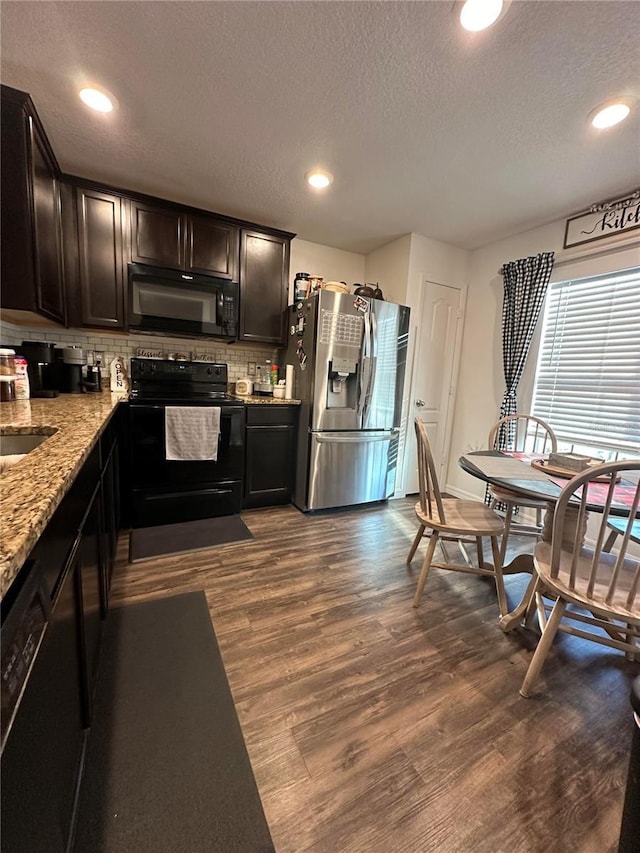 kitchen with a textured ceiling, dark wood-style flooring, backsplash, light stone countertops, and black appliances