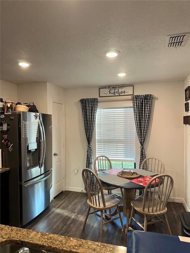 dining space featuring a textured ceiling, dark wood-style flooring, visible vents, and baseboards