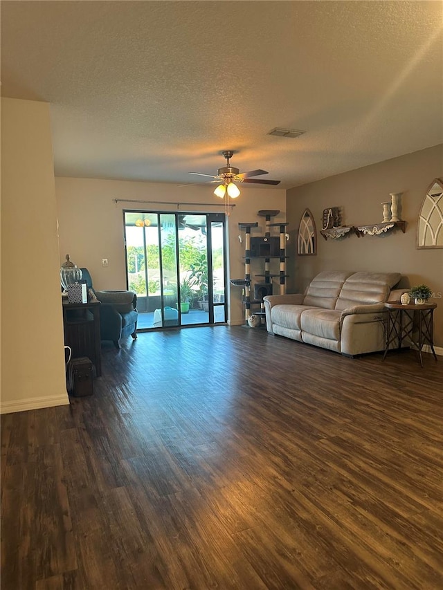 living area featuring a textured ceiling, dark wood-style flooring, visible vents, baseboards, and a ceiling fan