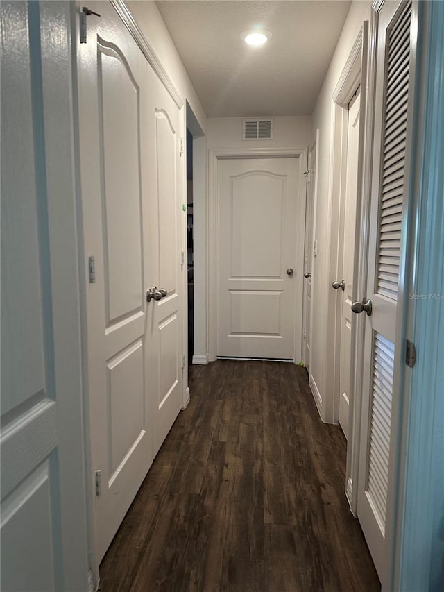 corridor featuring dark wood-style flooring and visible vents