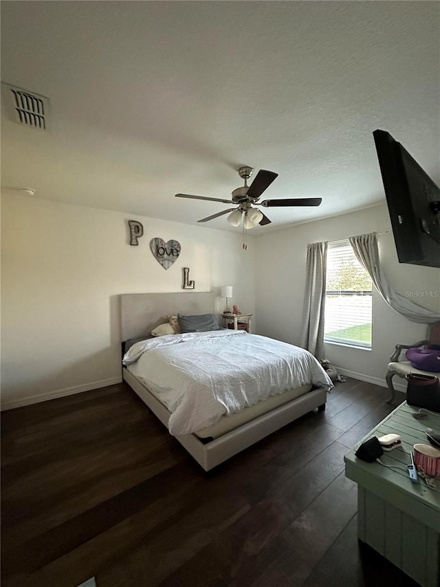 bedroom with a ceiling fan, baseboards, visible vents, and wood finished floors