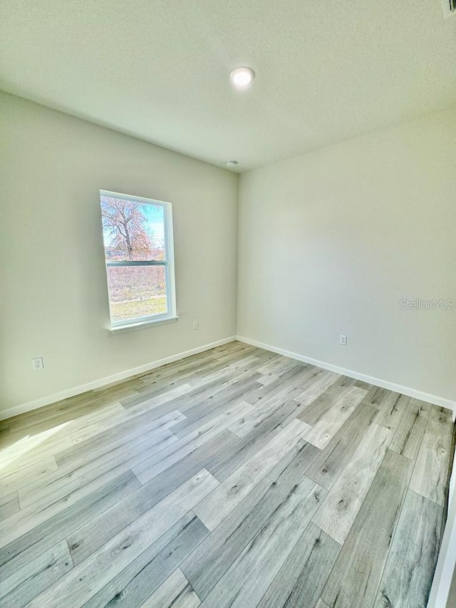 unfurnished room featuring light hardwood / wood-style flooring and a textured ceiling