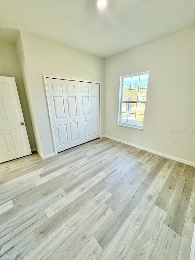 unfurnished bedroom with light wood-type flooring and a closet