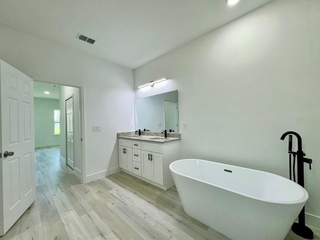 bathroom featuring a bath, wood-type flooring, and vanity