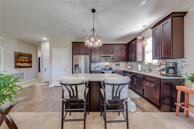 kitchen featuring light wood-type flooring, decorative light fixtures, a center island, and stainless steel appliances