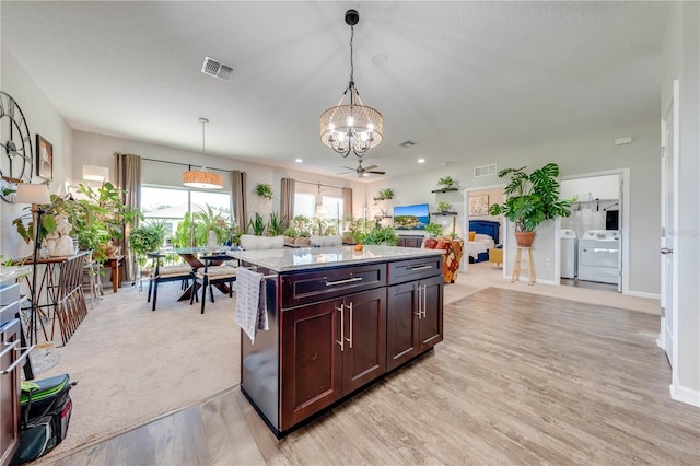 kitchen with a kitchen island, decorative light fixtures, a notable chandelier, light hardwood / wood-style floors, and light stone counters