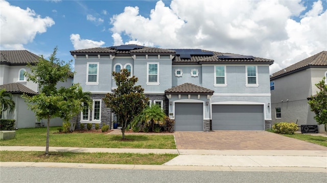 mediterranean / spanish-style house featuring a garage, solar panels, and a front lawn