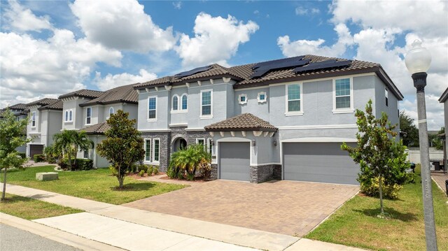 mediterranean / spanish-style house featuring a garage, solar panels, and a front yard