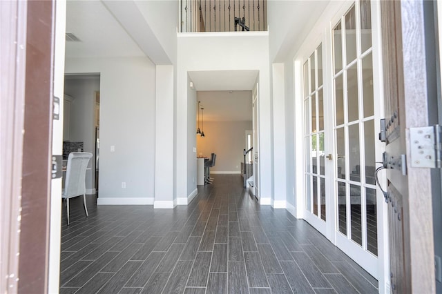 hallway featuring wood finish floors, visible vents, and baseboards