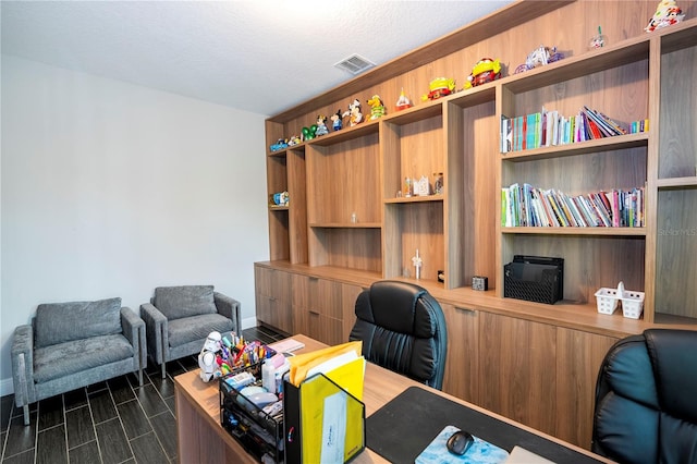 office space featuring a textured ceiling, built in desk, and visible vents