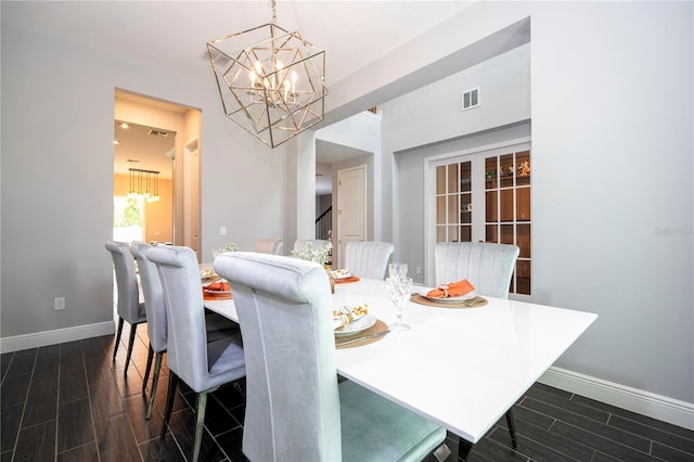 dining room with a chandelier, wood finish floors, visible vents, and baseboards