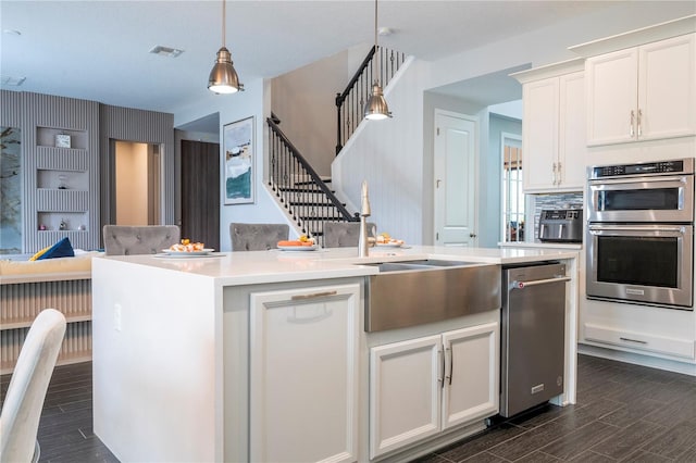 kitchen with wood tiled floor, appliances with stainless steel finishes, white cabinets, and light countertops