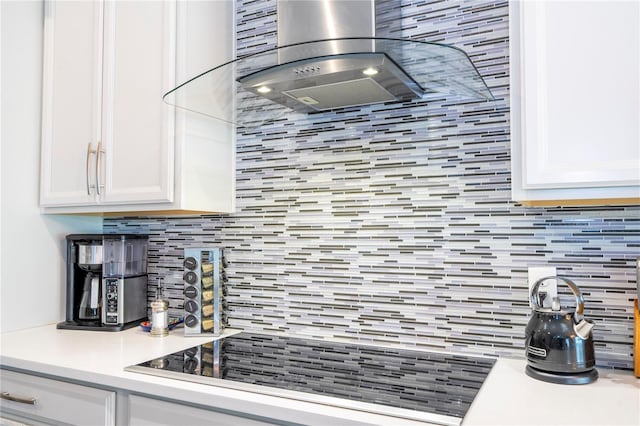 kitchen featuring tasteful backsplash, black electric stovetop, light countertops, white cabinetry, and exhaust hood