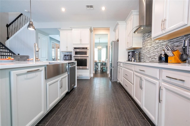 kitchen with white cabinetry, appliances with stainless steel finishes, backsplash, wood tiled floor, and wall chimney exhaust hood